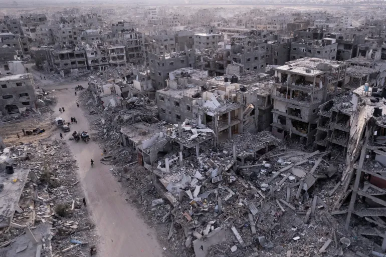 Fotografija snimljena dronom iz zraka prikazuje Palestince kako hodaju kroz ruševine nastale izraelskom zračnom i kopnenom ofanzivom u Gazi [Mohammad Abu Samra/AP]